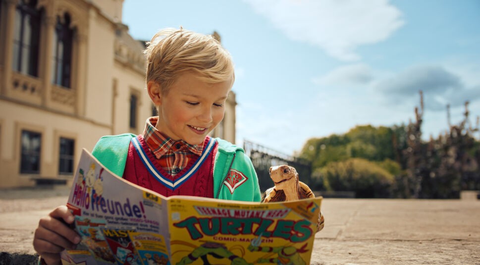 Benni (Leonard Conrads) und seine Schildkröte lesen ein Comic-Heft in dem Film Die Schule der magischen Tiere