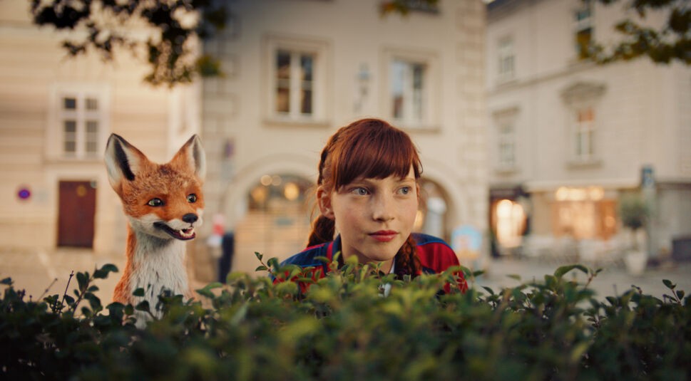 Ida (Emilia Maier) und ihr Fuchs schauen über eine Hecke im Film Die Schule der magischen Tiere