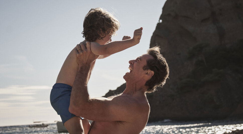 Peter hält Nicholas am Strand in die Luft