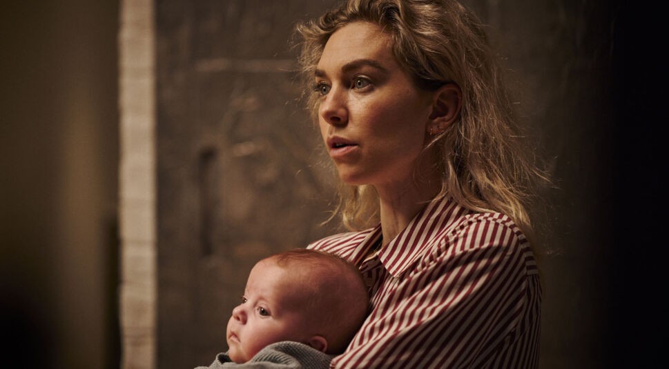 Beth hält ein Baby im Arm und schau erstaunt