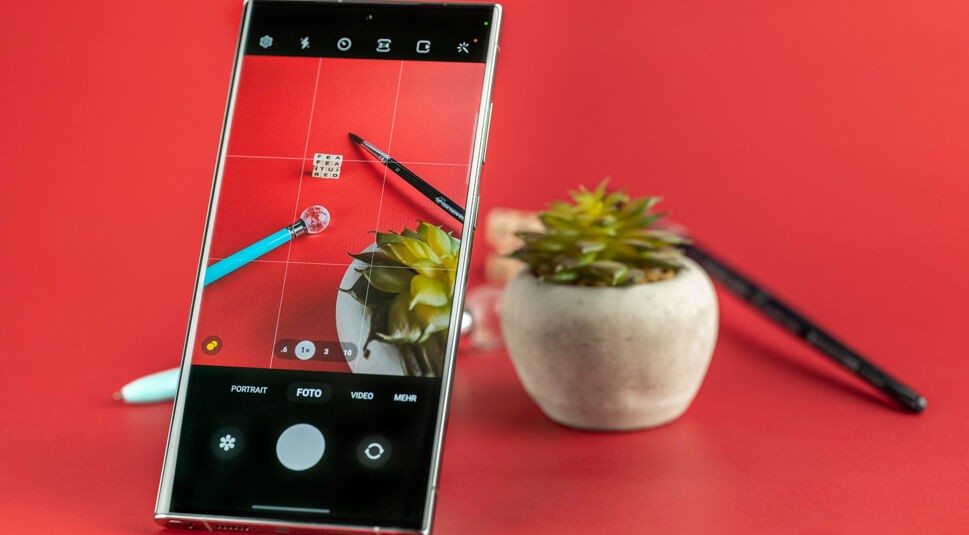 Display eines Smartphones zeigt Kaktus, Stifte und Buchstabenwürfel