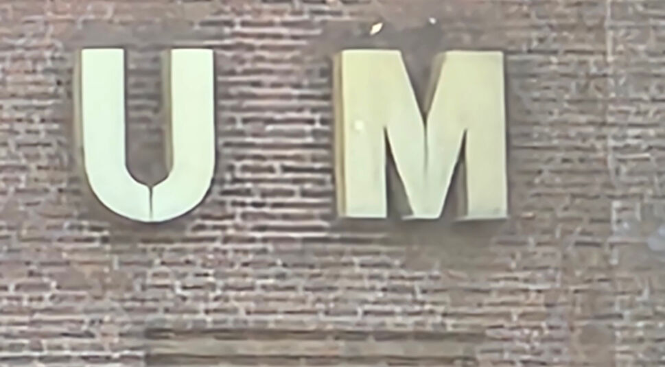 Zwei Buchstaben U und M an einem roten Backsteingebäude