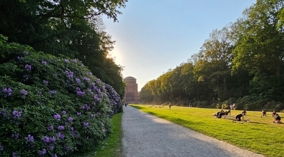 Ein mit Büschen und Bäumen gesäumter Weg, der auf einen roten Backsteinturm zuläuft, das Hamburger Planetarium
