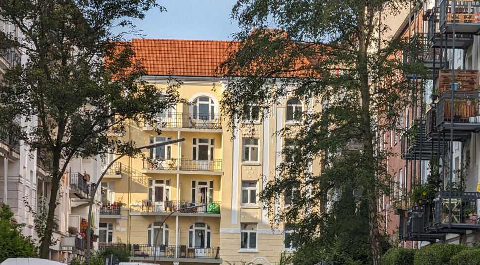 Gelbes Haus mit Bäumen davor, blauer Himmel darüber