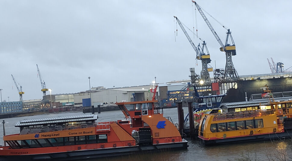 Zwei Hafenkräne im Morgengrauen, im Vordergrund Hafenfähren