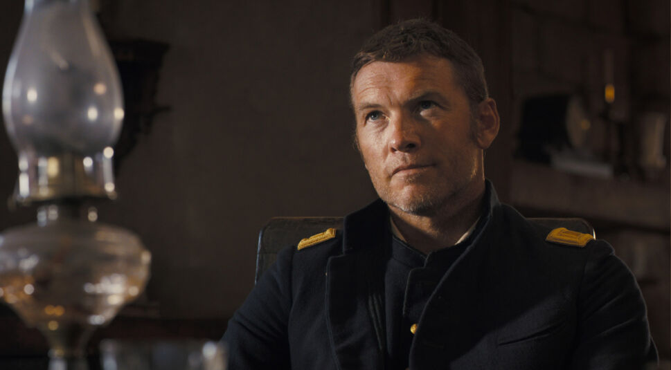 Sam Worthington in einer Uniform. Er schaut nach oben.