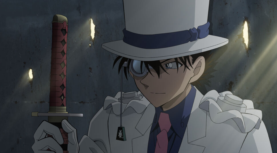 Im Bild im Artikel zum Kinofilm Detektiv Conan Film 27: Das 1-Million-Dollar-Pentagramm ist die Figur Kaito Kid zu sehen. Der Bildausschnitt zeigt die animierte Anime-Figur im Brustbild. Der Meisterdieb hält in seiner Hand ein Schwert mit dem Griff nach oben und blickt leicht lächelnd und mit verschmitztem Blick darauf. Der Schwertgriff ist im Bild links von seinem Gesicht. Die Figur trägt einen hellgrauen Blazer mit Rüschen auf den Schultern. Darunter ein dunkelblaues Hemd und iene rosane Krawatte, Seine Haut im Gesicht ist hell. Über dem im Bild linken Auge trägt er eine Art Vergrößerungsglas. Daran oder an seinem Hut baumelt eine Schnur mit einem klienen Griff am Ende, als könnte man daran ziehen. Sein Zylinder hat den selben hellen Grauton, wie der Anzug. Um den Hut herum liegt ein dunkelblaues Band, passend zum Hemd. Unter dem Hut schauen schwarze Haare heraus und hängen über den Augen. Im Hintergrund ist eine raue, dunkelgraue Wand zu sehen. Darin befinden sich einige Schlitze, durch die gelbes Licht dringt.