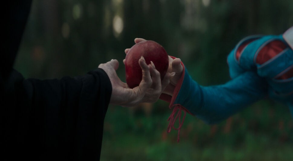 In einer Szene aus der Schneewittchen Realverfilmung überreicht die verkleidete Böse Königin Schneewittchen einen roten, vergifteten Apfel.