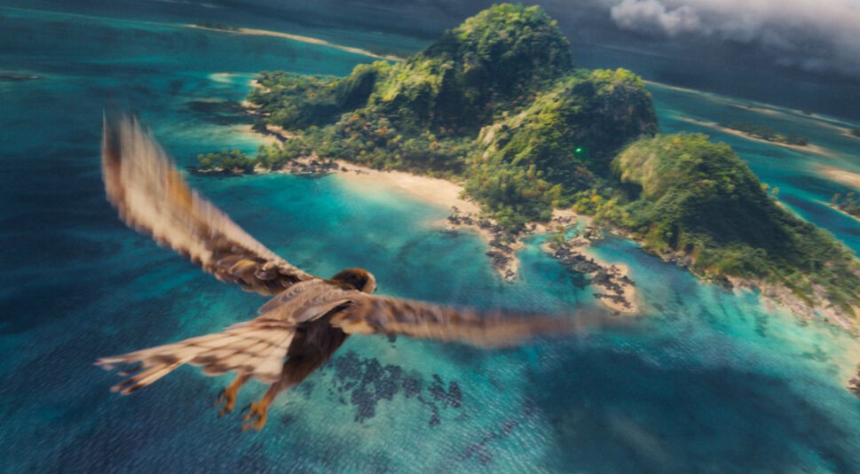 In dieser Aufnahme aus der Vaiana-Realverfilmung fliegt ein majestätischer Vogel über die üppig bewachsene Insel Motunui. Das türkisfarbene Wasser umrahmt die paradiesische Landschaft mit dichten Wäldern, weißen Stränden und steilen Felsen.