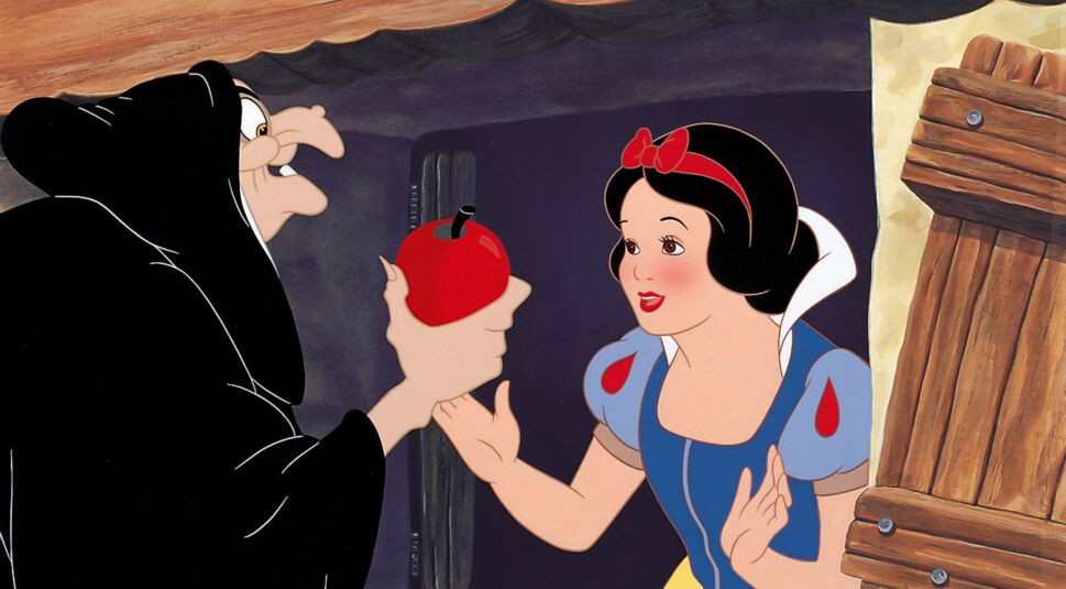 Auf dem Bild aus Schneewittchen und die sieben Zwerge (Disney, 1937) ist Schneewittchen in ihrem ikonischen blauen Kleid mit roten Akzenten zu sehen. Sie blickt freundlich auf die alte Hexe, die ihr einen glänzend roten Apfel anbietet. Die Szene ist stilistisch klassisch animiert und stellt einen Schlüsselmoment der Disney-Geschichte dar. Dieses Bild illustriert den visuellen Stil des Originals im Vergleich zu Schneewittchen (2025).