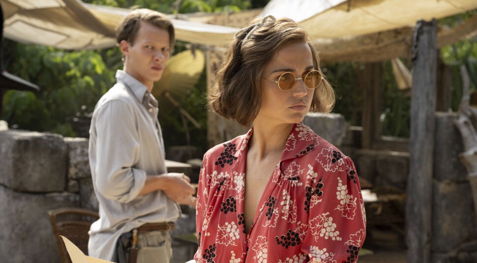 Im Mittelpunkt dieser Szene aus dem Film Eden, inspiriert von einer wahren Geschichte, stehen Ana de Armas als Baronin Eloise Bosquet de Wagner Wehrhorn in auffälliger roter Bluse mit Sonnenbrille und Felix Kammerer als Rudolf Lorenz im Hintergrund. Der Blick der beiden verrät Spannung und Unruhe – ein Moment, der die konfliktreiche Dynamik widerspiegelt.