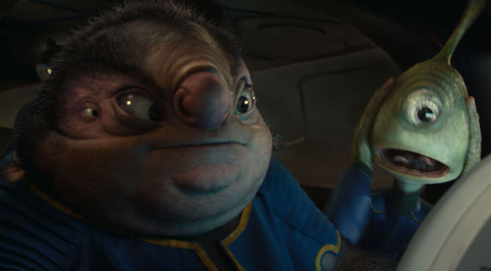 Auf dem Bild in dem Artikel zum Lilo & Stitch-Vergleich sind Jumba Jookiba und Pleakley in der Live-Action-Version von 2024 zu sehen. Jumba, ein Alien mit markanter Stirn, schaut ernst zur Seite, während Pleakley – ein einäugiges, grünes Wesen – sich panisch die Hände an den Kopf legt. Beide tragen blaue Raumanzüge. Die Szene wirkt hektisch und humorvoll zugleich.