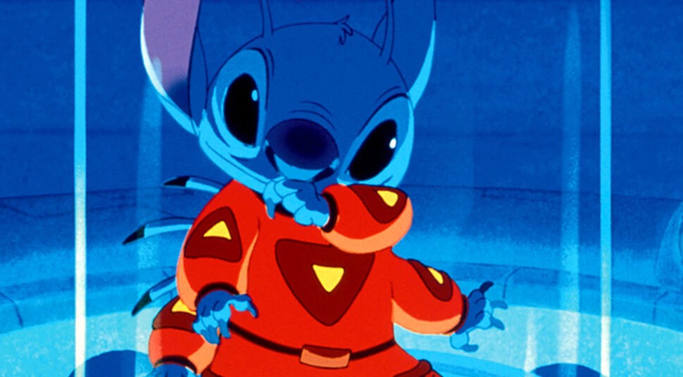 Auf dem Bild in dem Artikel zum Lilo & Stitch-Vergleich ist Stitch aus dem Originalfilm von 2002 zu sehen. Er trägt einen roten Raumanzug mit gelben Symbolen und befindet sich in einer Glaskammer.