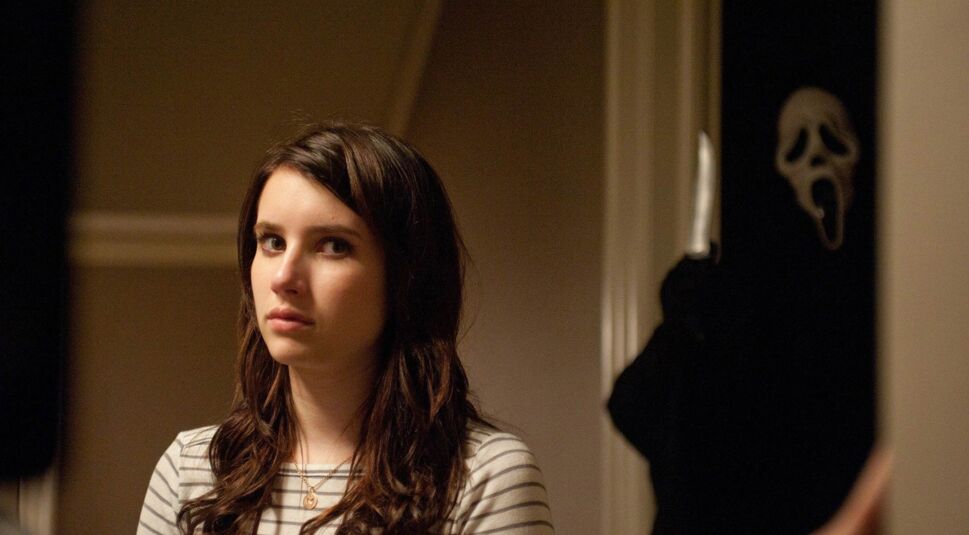 In den GigaTV-Highlights im Oktober 2025 ist eine Szene aus dem Film „Scream 4“ zu sehen. Im Vordergrund steht Emma Roberts in der Rolle von Jill Roberts mit neutralem Gesichtsausdruck. Im Hintergrund erscheint die Figur Ghostface in schwarzer Kleidung und mit weißer Maske, die ein Messer in der erhobenen Hand hält.