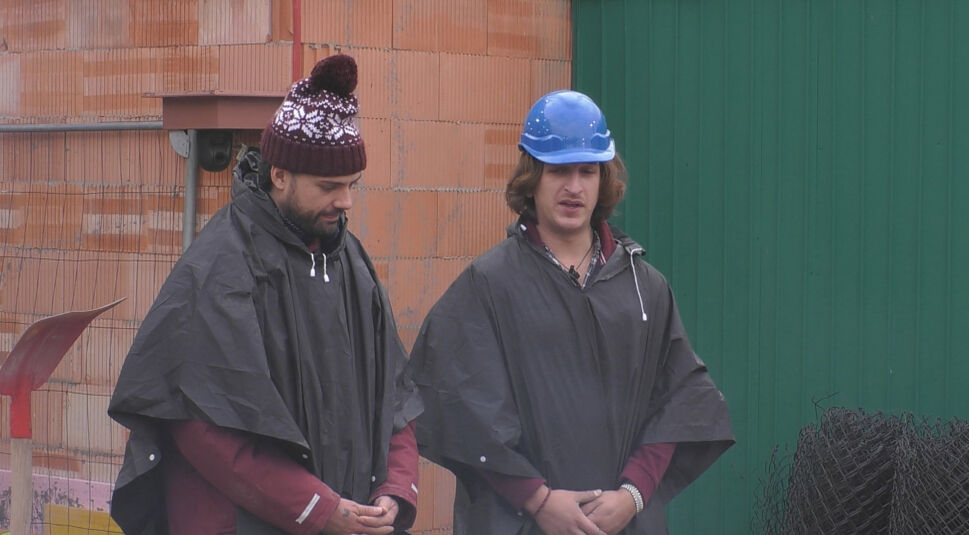 In dieser Szene aus „Promi Big Brother“ 2025 stehen zwei männliche Bewohner draußen vor einer Wand.