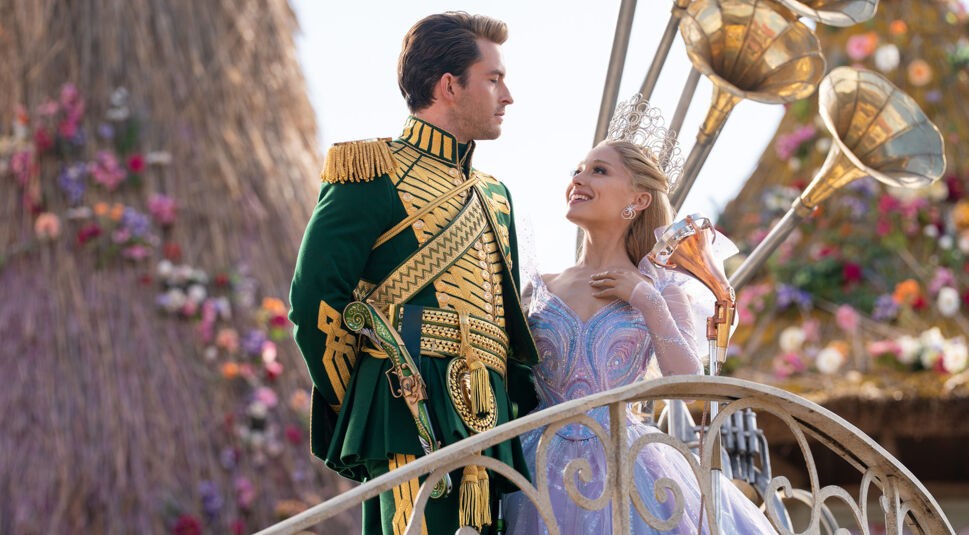 Auf dem Bild in dem Artikel zur „Wicked: Teil 2“-Kritik steht Glinda, gespielt von Ariana Grande, lächelnd neben Prinz Fiyero, gespielt von Jonathan Bailey.