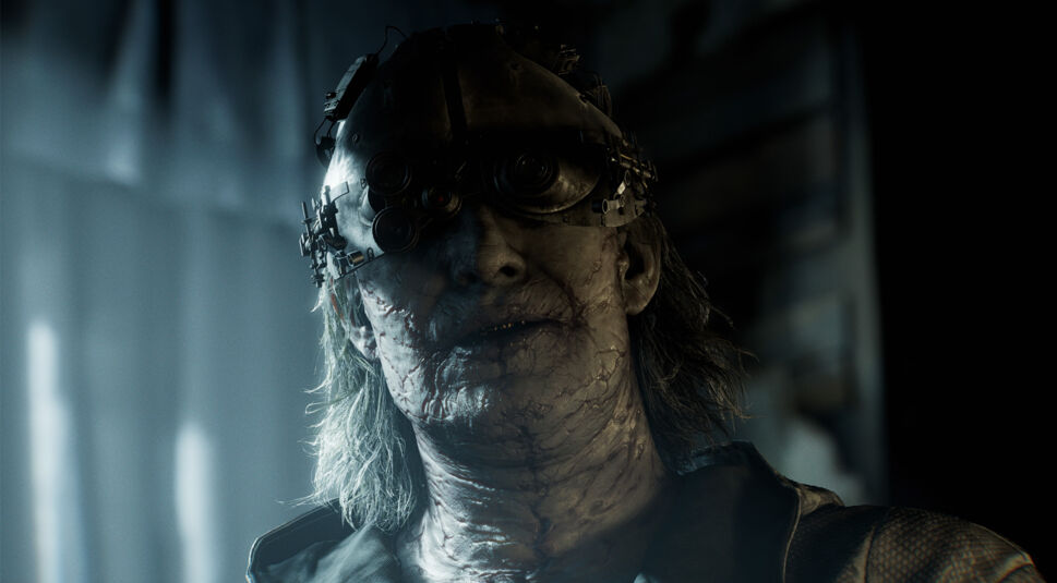 Viktor Gideon ist auf diesem Bild als einer der Resident Evil Requiem Charaktere zu sehen. Er trägt eine groteske Metallmaske mit mehreren Linsen über den Augen und hat stark vernarbte, kranke Haut. Sein langes, graues Haar fällt wirr über die Schultern. Die Szene ist unheimlich und düster, mit kaltem Licht und gruseligem Klinikflair.