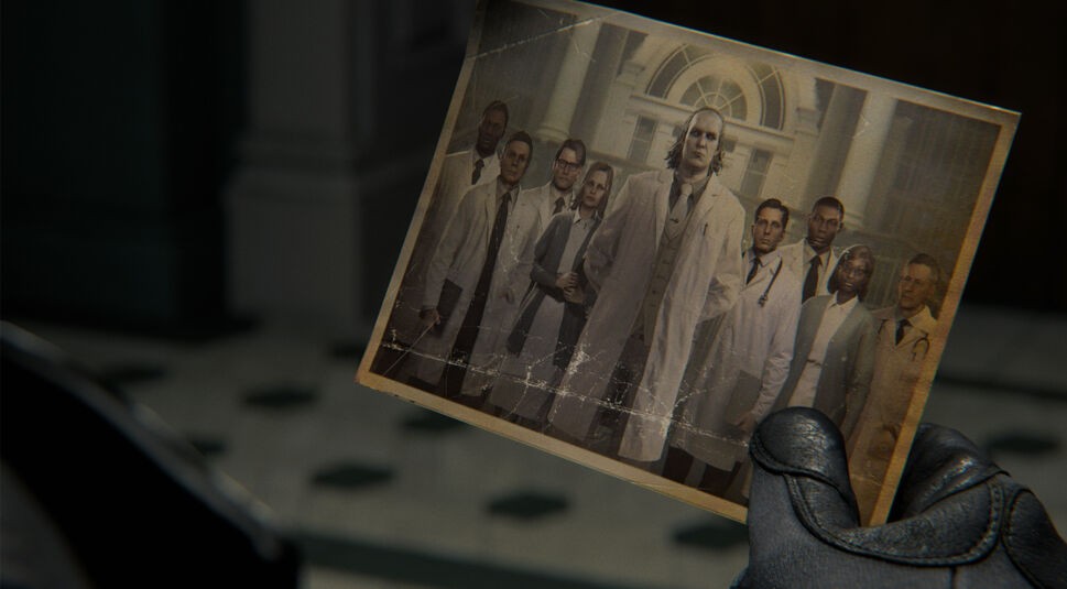 Auf dem gezeigten Gruppenfoto sind mehrere Wissenschaftler als Resident Evil Requiem Charaktere zu sehen. Im Zentrum steht Viktor Gideon im weißen Kittel, umgeben von einem Forscherteam vor einem historischen Gebäude. Das Foto wirkt alt und vergilbt, mit sichtbaren Knicken – ein Hinweis auf eine düstere Vergangenheit und tragische Ereignisse in der Spielwelt.