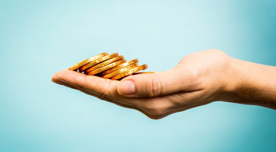 Hand holding golden coins concept on blue background. Business c