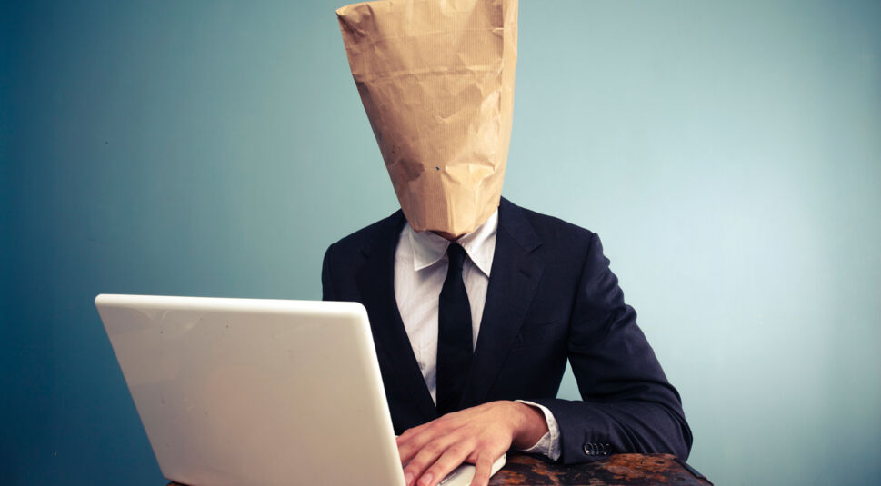 Businessman with bag over head working on computer