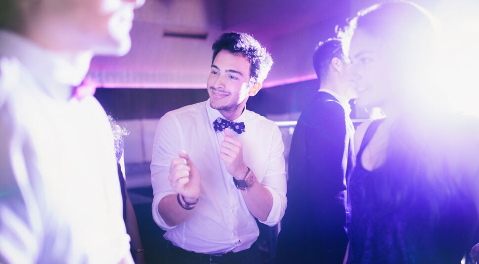 Sweet, nerdy looking guy showing off some dancemoves on the dance floor in a club with friends