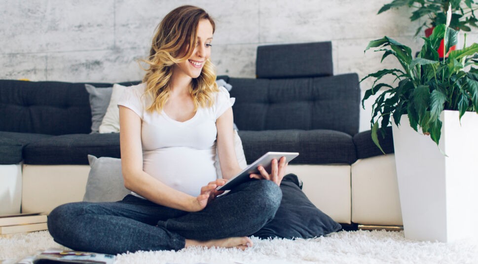 Pregnant woman using digital tablet at home