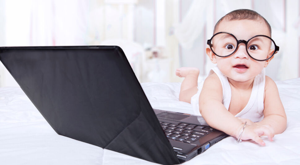 Sweet male baby with glasses and laptop
