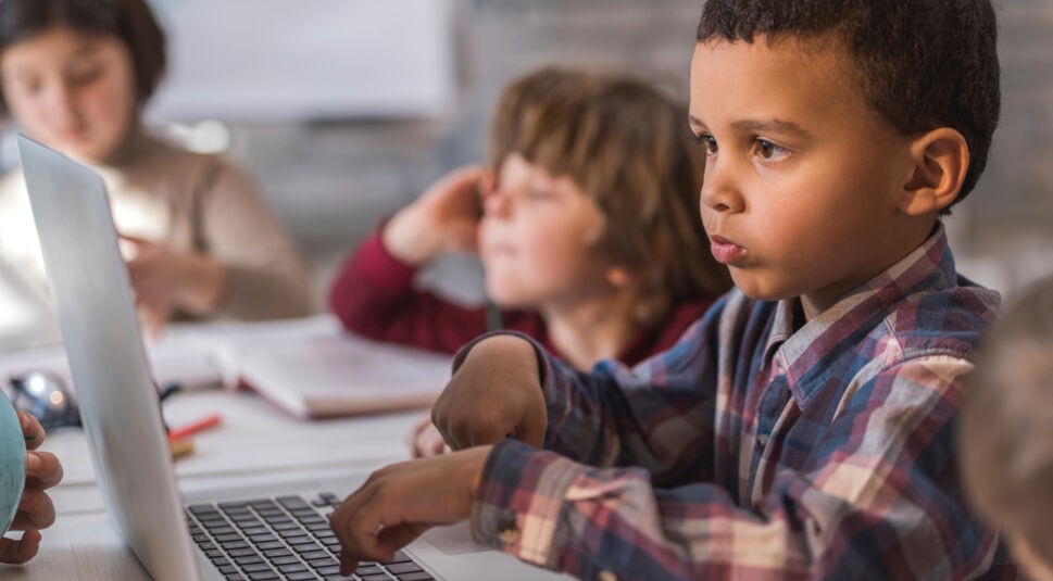 Creative African American little boy typing on laptop.