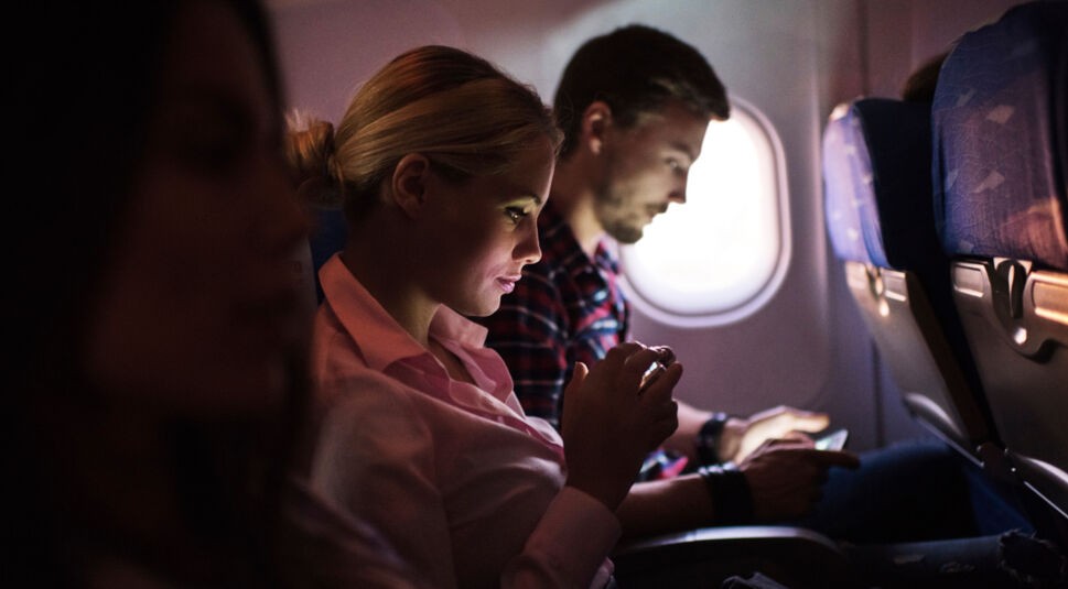 Woman using smart phone in airplane.