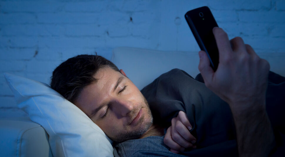 young man in bed couch at home falling asleep late at night whil