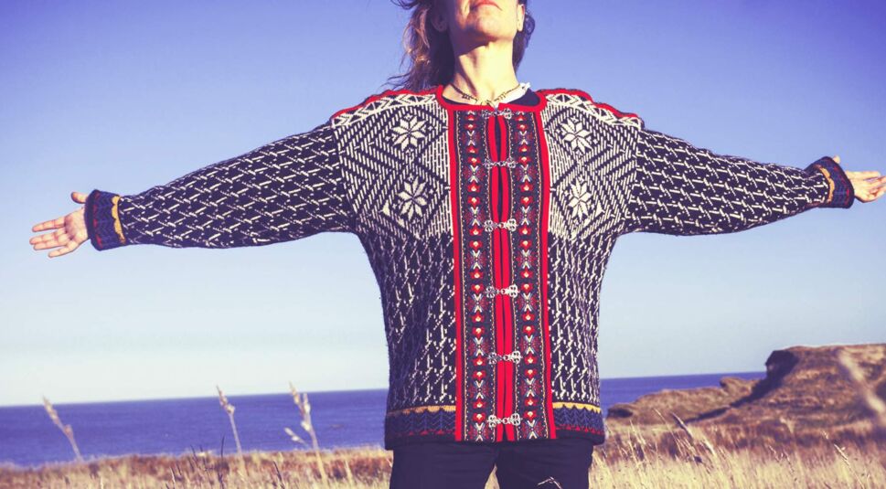 Young woman throwing her arms back  in meadow by the sea