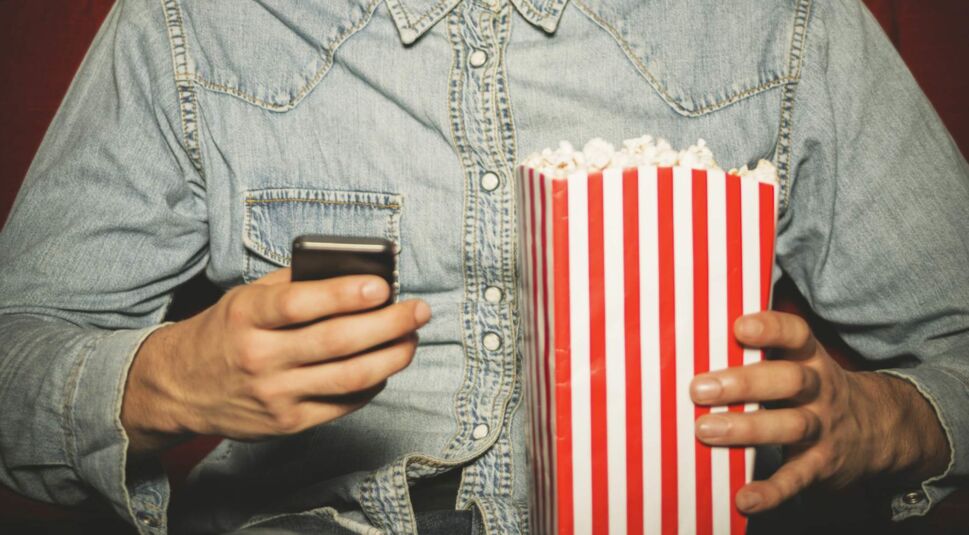 Young man using his phone at the cinema