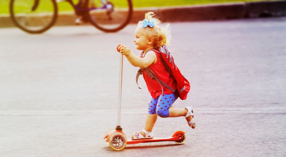 cute little toddler girl riding scooter in the city