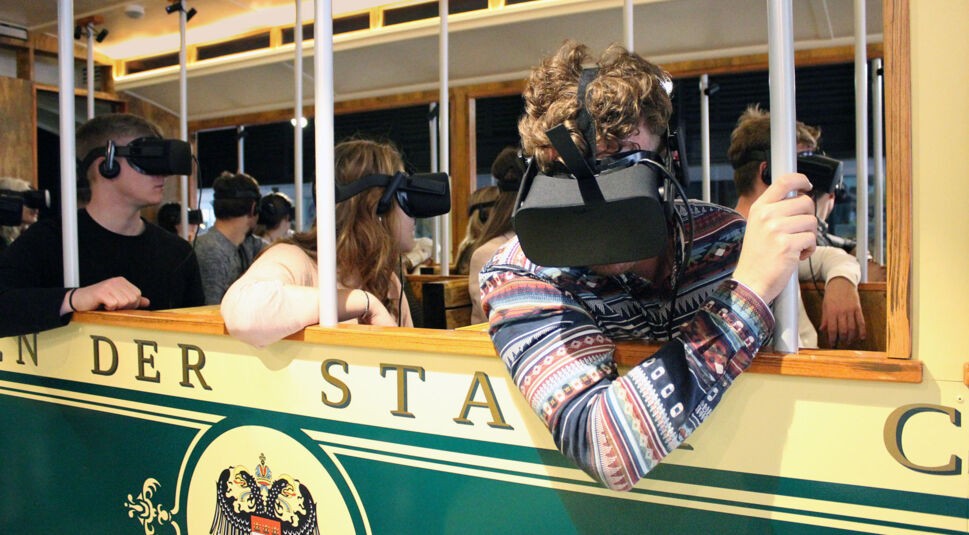 Menschen sitzen mit VR-Brillen in einer historischen Straßenbahn bei der VR-Zeitreise von Timeride in Köln. 