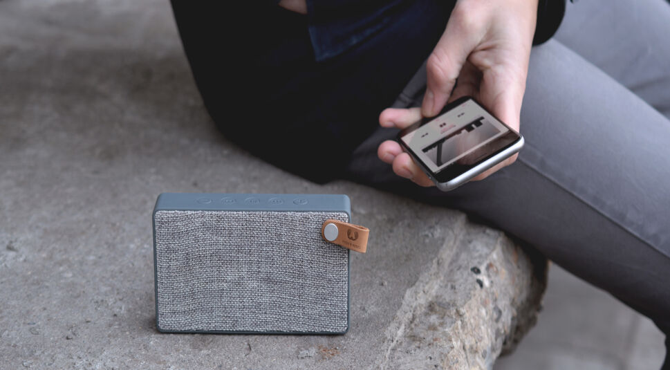 Die Fresh n Rebel Soundbox Fabric Slice auf einer Mauer mit Handy