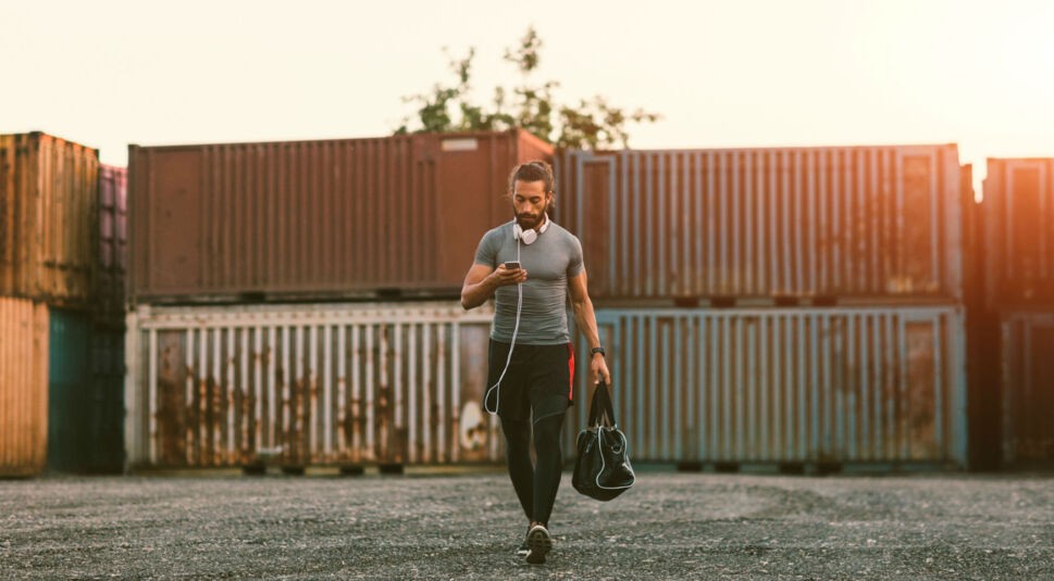 Mann in Sportlerkleidung betrachtet sein Smartphone