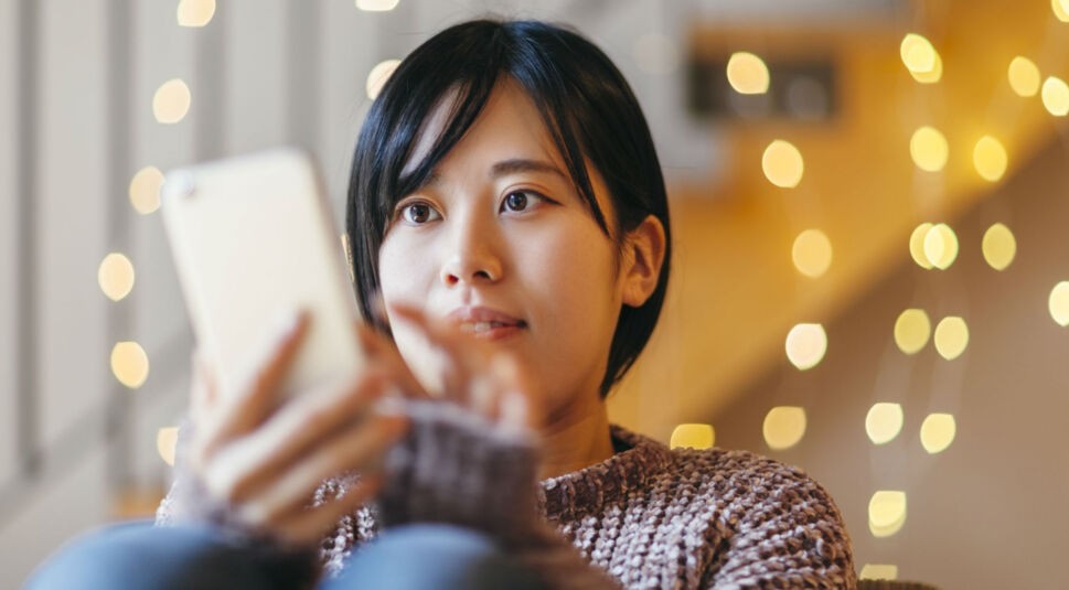 Junge Frau erhält eine Nachricht übers Smartphone.