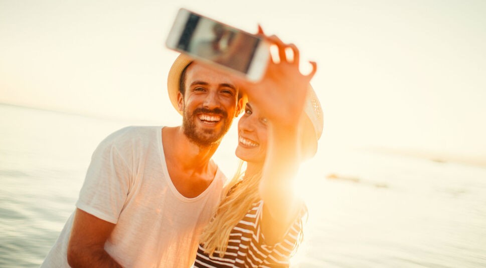 Ein Paar schießt im Urlaub Fotos mit dem Smartphone.