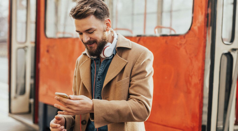 Junger Mann erhält auf dem Weg zur Arbeit eine Benachrichtigung am Smartphone.