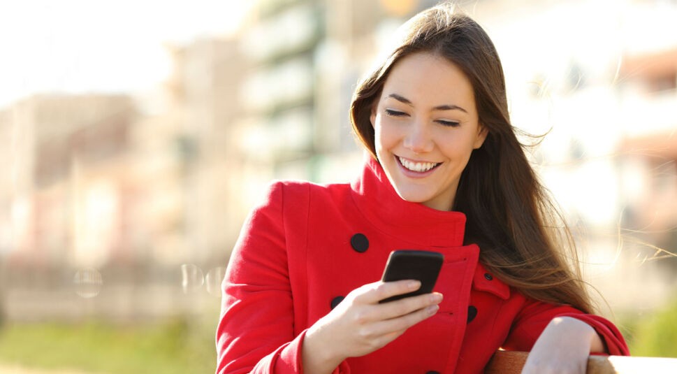 Frau im roten Mantel mit Smartphone in der Hand