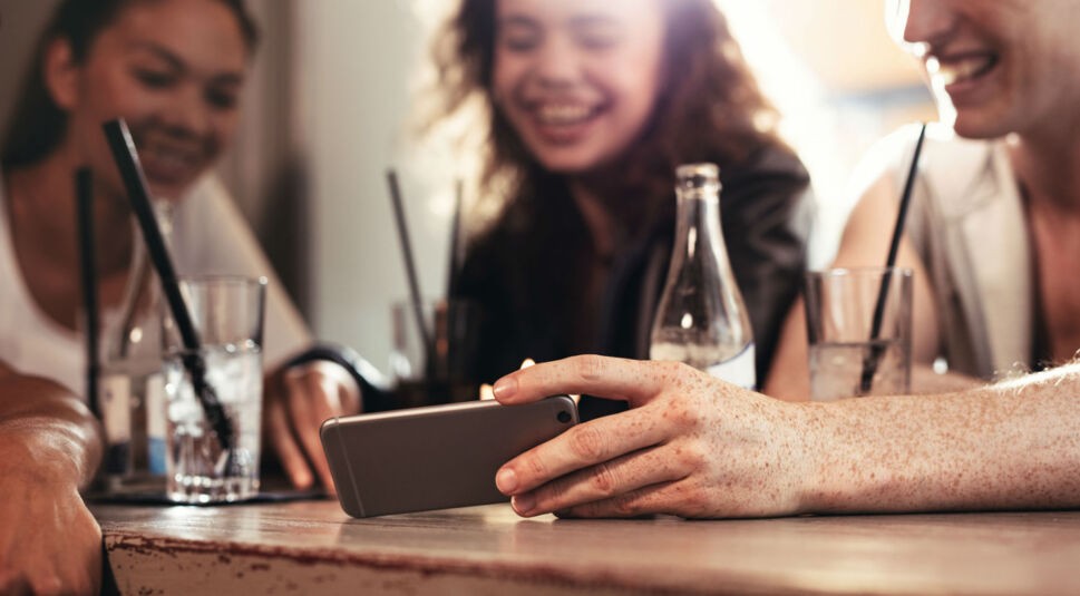 Freunde gucken auf ein Smartphone.