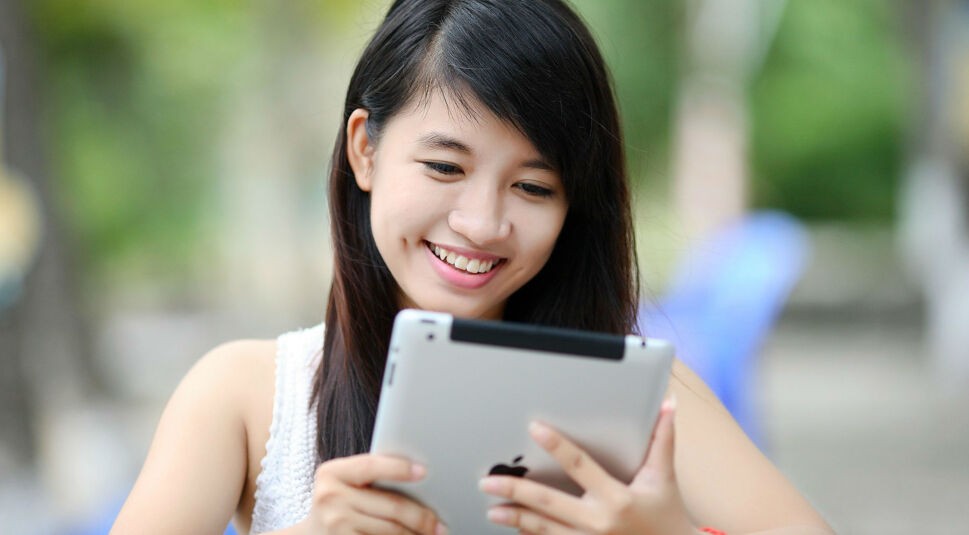 Mädchen sitzt lächelnd am iPad.