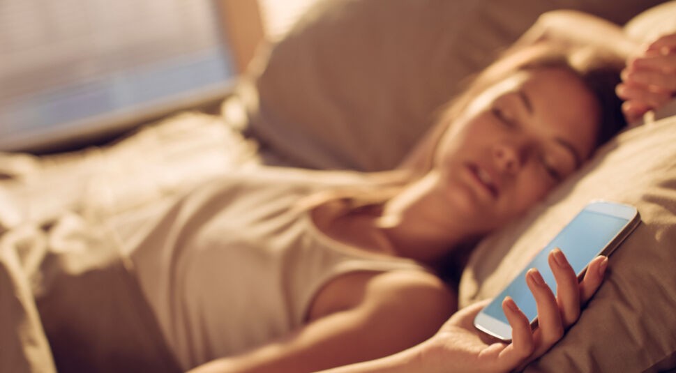 Frau schläft neben Smartphone mit Android Oreo.