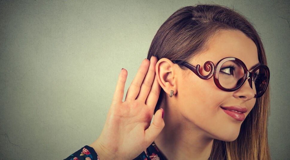 Frau spitzt die Ohren und lauscht auf Google Home