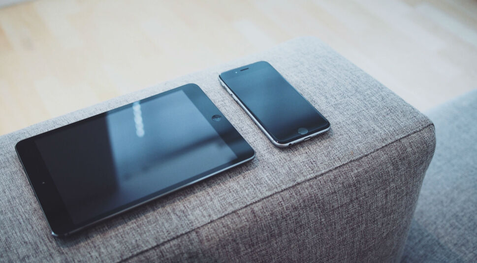 iPad und iPhone liegen auf dem Sofa.