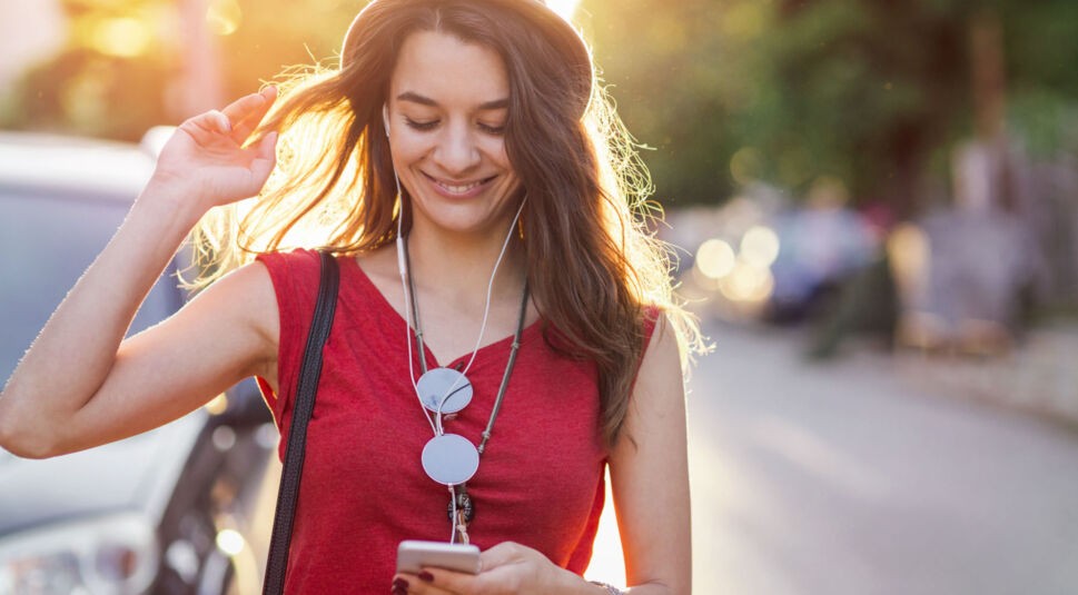 Mädchen in rotem Shirt mit Smartphone in der Hand.