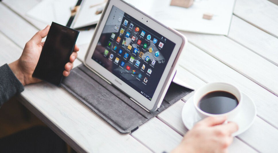 Smartphone, Samsung-Tablet und eine Tasse Kaffee auf dem Tisch.
