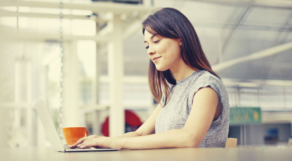 Junge Frau tippt an ihrem Laptop.