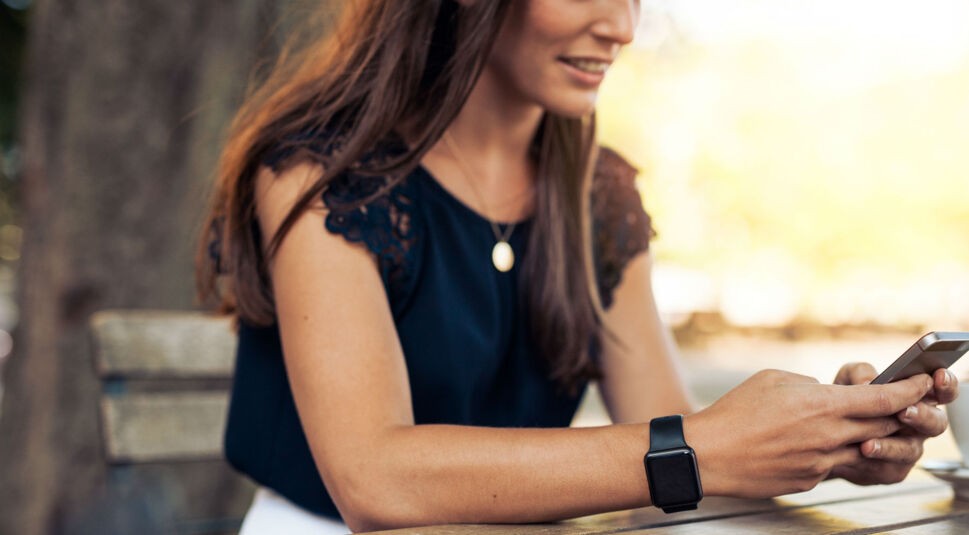 Junge Frau sitzt auf einer Bank und lächelt.