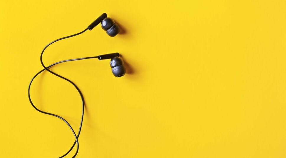 Schwarze In-Ear-Kopfhörer auf knallgelbem Hintergrund.